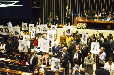 01/04/2014. Crédito: Renato Costa/Frame/Agência O Globo. Brasil. Brasília-DF. Parlamentares e ativistas viram-se de costas e erguem cartazes com as fotos de desaparecidos políticos do regime militar como forma de protesto à fala do deputado Jair Bolsonaro, defensor do golpe, na sessão solene da câmara dos Deputados sobre os 50 anos do golpe militar de 1964.
- (crédito: Renato Costa/Frame/Agência O Globo) 01/04/2014. Crédito: Renato Costa/Frame/Agência O Globo. Brasil. Brasília-DF. Parlamentares e ativistas viram-se de costas e erguem cartazes com as fotos de desaparecidos políticos do regime militar como forma de protesto à fala do deputado Jair Bolsonaro, defensor do golpe, na sessão solene da câmara dos Deputados sobre os 50 anos do golpe militar de 1964.
- (crédito: Renato Costa/Frame/Agência O Globo)