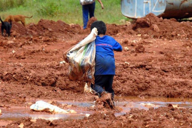Criança enfrenta a lama para levar para casa uma cesta básica doada: 33 milhões de brasileiros não conseguem se alimentar adequadamente - 