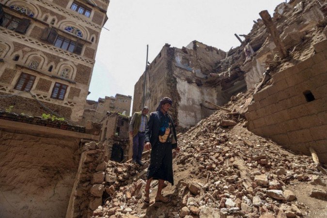 Homens iemenitas inspecionam os danos no local de um prédio desabado listado pela UNESCO após fortes chuvas, na cidade velha da capital do Iêmen, Sanaa. -  (crédito: Mohammed HUWAIS / AFP)