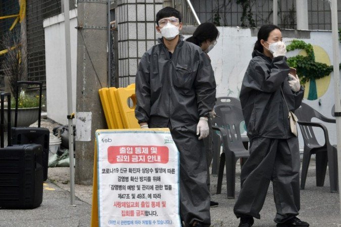 Funcionários do governo vestindo roupas de proteção estão em um posto de controle temporário para restringir o acesso à Igreja Sarang Jeil em Seul em 17 de agosto de 2020. - (foto: Jung Yeon-je / AFP) Funcionários do governo vestindo roupas de proteção estão em um posto de controle temporário para restringir o acesso à Igreja Sarang Jeil em Seul em 17 de agosto de 2020. - (foto: Jung Yeon-je / AFP)