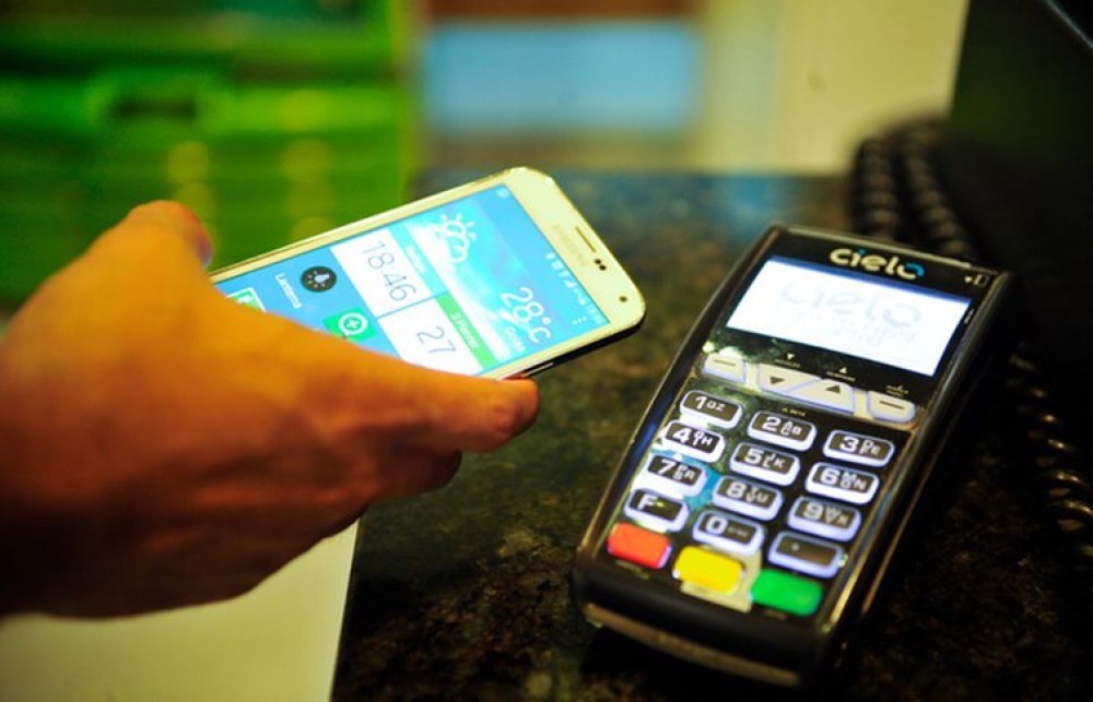 Pagamento com celular em máquina de cartão de crédito e débito.