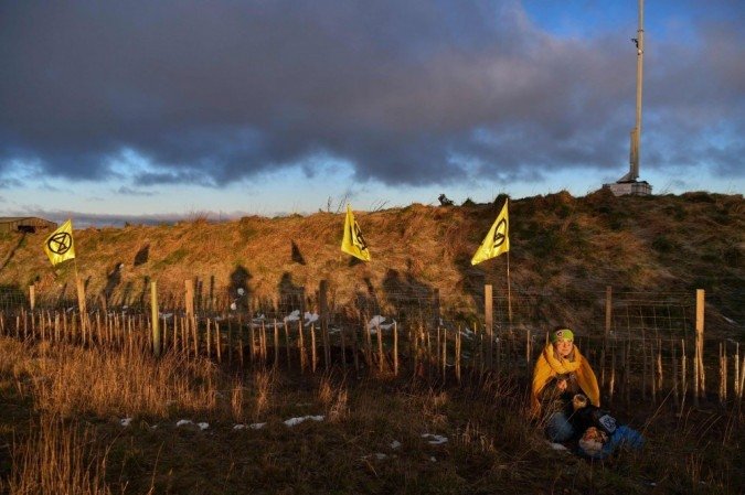 Um ativista do grupo de ação climática Extinction Rebellion está sentado em uma grama enquanto ativistas bloqueiam a entrada do local da mina de carvão a céu aberto Bradley perto da vila de Leadgate no Pont Valley em County Durham, nordeste da Inglaterra, em 26 de fevereiro, 2020 no início de um bloqueio de três dias. - (foto: AFP / Paul ELLIS) Um ativista do grupo de ação climática Extinction Rebellion está sentado em uma grama enquanto ativistas bloqueiam a entrada do local da mina de carvão a céu aberto Bradley perto da vila de Leadgate no Pont Valley em County Durham, nordeste da Inglaterra, em 26 de fevereiro, 2020 no início de um bloqueio de três dias. - (foto: AFP / Paul ELLIS)