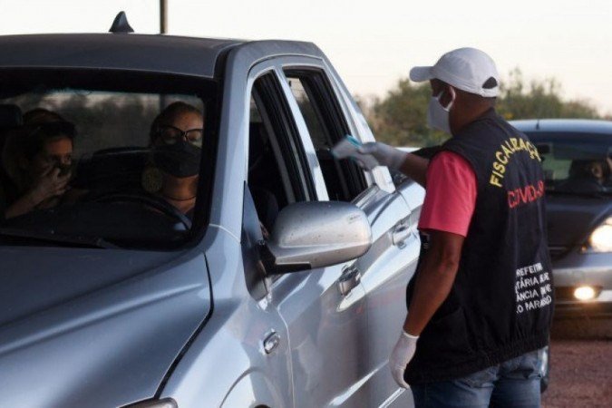Agentes de saúde aferem a temperatura de visitantes, na entrada da cidade