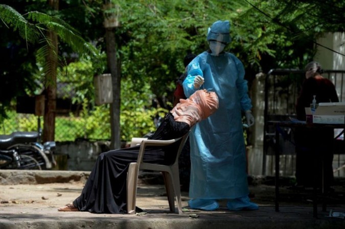 Profissional de saúde usa cotonete para colher amostra de mulher suspeita de ter covid-19, em Hyderabad - (foto: Noah Seelam/AFP)