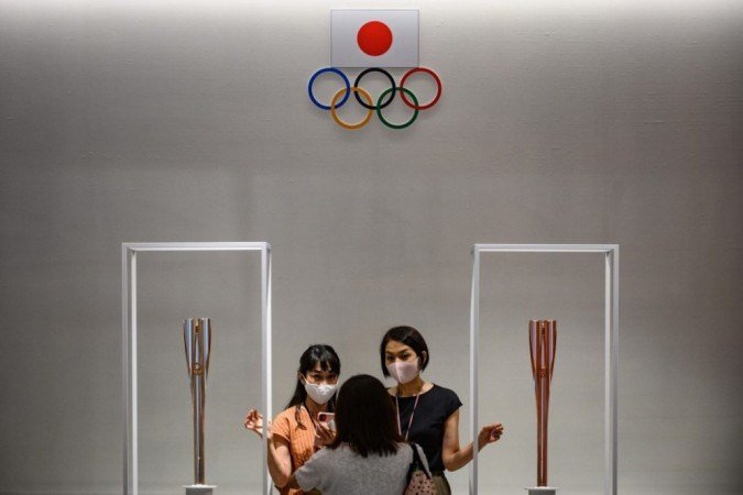 Pessoas posam para fotos com a tocha olímpica de revezamento (E) e a tocha de revezamento paraolímpica (D) no Museu Olímpico de Tóquio em 1º de setembro de 2020. - (foto: Philip FONG / AFP) Pessoas posam para fotos com a tocha olímpica de revezamento (E) e a tocha de revezamento paraolímpica (D) no Museu Olímpico de Tóquio em 1º de setembro de 2020. - (foto: Philip FONG / AFP)