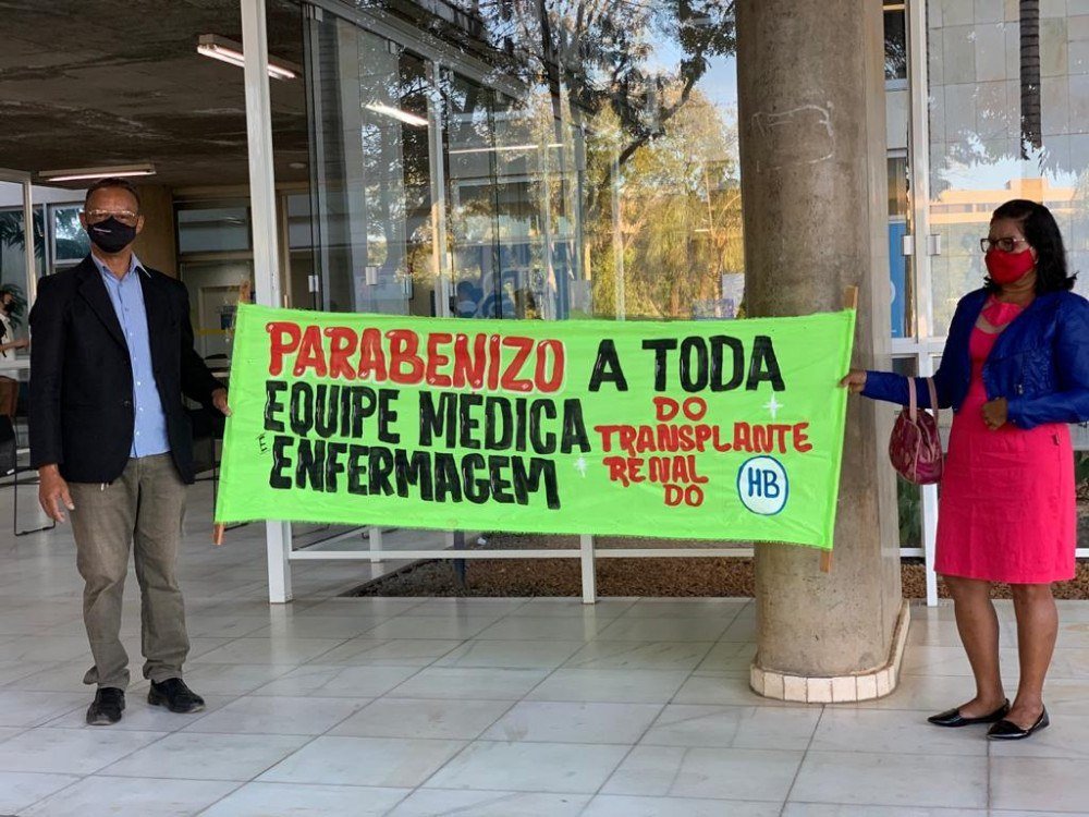 Paciente segura faixa de gratidão em frente ao Hospital de Base