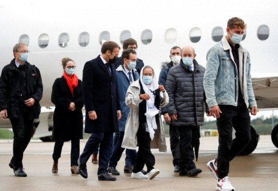 O presidente francês Emmanuel Macron (D) fica ao lado da trabalhadora humanitária francesa Sophie Petronin (C), que é recebida por sua família depois que supostos sequestradores jihadistas libertaram a mulher de 75 anos após quase quatro anos de cativeiro em Mali após sua chegada ao Aeroporto militar Villacoublay perto de Paris em 9 de outubro de 2020. Petronin foi libertada junto com um importante político do Mali e dois reféns italianos no final de 8 de outubro de 2020. A última cidadã francesa conhecida por ter sido mantida refém em qualquer lugar do mundo desde seu sequestro em 2016 , uma Petronin vestida de branco foi abraçada por seu filho quando pousou na capital do Mali, Bamako.