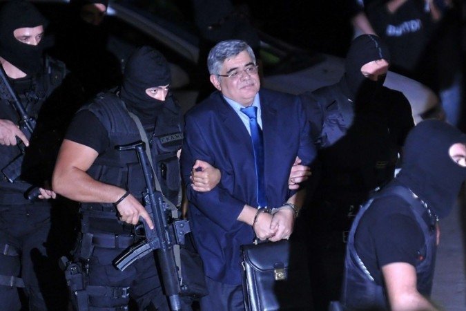 Nesta foto de arquivo tirada em 2 de outubro de 2013, o líder do partido neonazista grego Golden Dawn Nikos Michaloliakos (C) é escoltado por uma polícia mascarada a um tribunal de Atenas. - (crédito: LOUISA GOULIAMAKI / AFP) Nesta foto de arquivo tirada em 2 de outubro de 2013, o líder do partido neonazista grego Golden Dawn Nikos Michaloliakos (C) é escoltado por uma polícia mascarada a um tribunal de Atenas. - (crédito: LOUISA GOULIAMAKI / AFP)