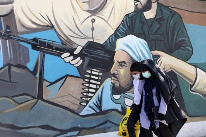 Mulheres iranianas usando máscaras passam por uma pintura mural na Praça da Palestina na capital iraniana, Teerã, em 18 de outubro de 2020, durante a nova crise de pandemia de coronavírus. - (crédito: ATTA KENARE / AFP) Mulheres iranianas usando máscaras passam por uma pintura mural na Praça da Palestina na capital iraniana, Teerã, em 18 de outubro de 2020, durante a nova crise de pandemia de coronavírus. - (crédito: ATTA KENARE / AFP)