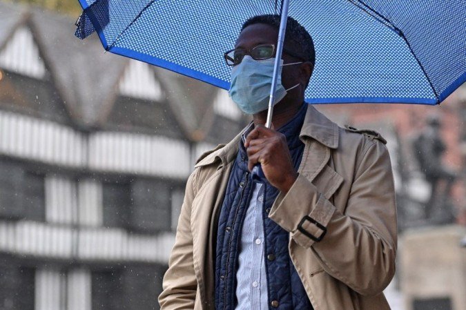 Um homem usando uma máscara de proteção facial se protege da chuva sob um guarda-chuva enquanto caminha ao longo de Holborn, no centro de Londres, em 21 de outubro de 2020, enquanto o governo considera novas medidas de bloqueio para combater o aumento de novos casos de coronavírus COVID-19. A Grã-Bretanha sofreu o pior número de mortes na Europa por coronavírus, com quase 44.000 mortes em 28 dias após um resultado de teste positivo. Depois da calmaria do verão, os casos estão crescendo novamente, como em outras partes do continente - assim como as mortes, com 241 registrados apenas na terça-feira.