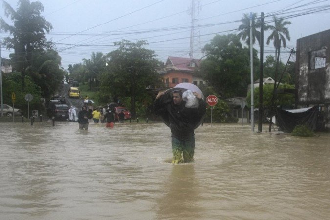 Um homem atravessa uma rua inundada devido às fortes chuvas causadas pelo furacão Eta, agora degradado em uma tempestade tropical, em Puerto Barrios, Izabal 310 km ao norte da Cidade da Guatemala em 5 de novembro de 2020. -  (crédito: Johan ORDONEZ / AFP)