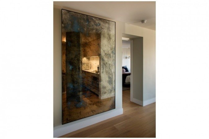 Nesse projeto da arquiteta Guta Louro, o corredor amplo permite o uso de um quadro maior sem que o espaço fique poluído. A iluminação e a forma de pendurar, usando um recuo, transformam o quadro em um ponto de atenção da decoração