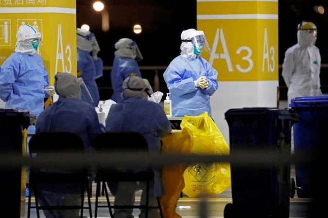 Trabalhadores de saúde em trajes de proteção esperando para realizar testes de coronavírus covid-19 na equipe do Aeroporto de Pudong, em Xangai, em 22 de novembro de 2020. - (crédito: STR / CNS / AFP) Trabalhadores de saúde em trajes de proteção esperando para realizar testes de coronavírus covid-19 na equipe do Aeroporto de Pudong, em Xangai, em 22 de novembro de 2020. - (crédito: STR / CNS / AFP)