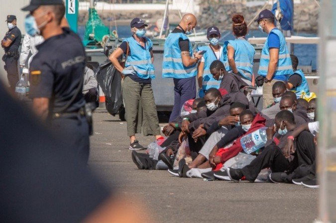 Migrantes esperam para serem transferidos para suas acomodações depois de serem resgatados pela guarda costeira espanhola nas Ilhas Canárias de Gran Canaria em 23 de novembro de 2020. - (crédito: DESIREE MARTIN / AFP) Migrantes esperam para serem transferidos para suas acomodações depois de serem resgatados pela guarda costeira espanhola nas Ilhas Canárias de Gran Canaria em 23 de novembro de 2020. - (crédito: DESIREE MARTIN / AFP)
