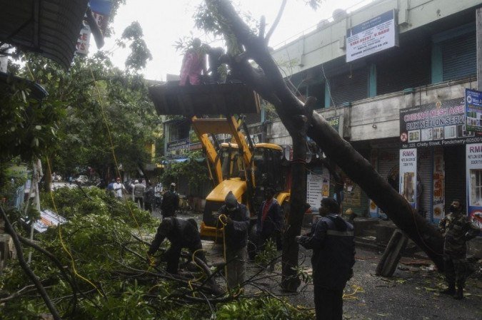 Equipes de emergência e resgate limpam a rua depois que uma árvore caiu devido a fortes chuvas e ventos fortes após a queda do ciclone Nivar, em Puducherry em 26 de novembro de 2020. - (crédito: Arun SANKAR / AFP) Equipes de emergência e resgate limpam a rua depois que uma árvore caiu devido a fortes chuvas e ventos fortes após a queda do ciclone Nivar, em Puducherry em 26 de novembro de 2020. - (crédito: Arun SANKAR / AFP)