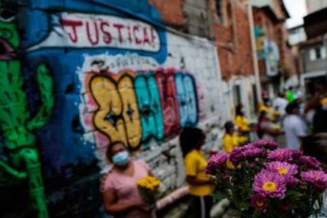 Residents of Paraisopolis, one of the city's largest slums, hold flowers during a protest in Sao Paulo, Brazil, on December 1, 2020. A year ago, nine people were trampled to death and twelve others were injured in a chaotic aftermath of a police raid. / AFP / Miguel SCHINCARIOL