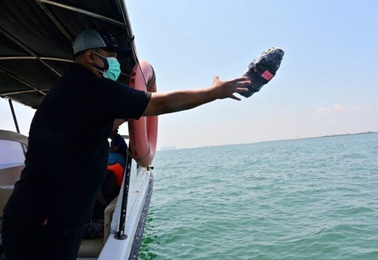 Esta foto tirada em 20 de outubro de 2020 mostra Eric Ragaputra, um técnico da empresa CLS Argos, jogando um dispositivo de monitoramento de plástico com balizas de satélite no mar para monitorar os resíduos na costa de Teluk Naga, Tangerang, província de Banten. 