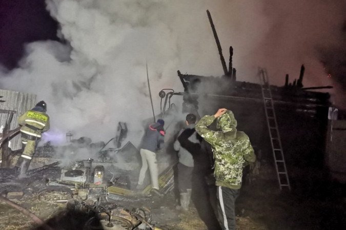 Homens e um bombeiro são vistos no local de um incêndio em uma casa de repouso na vila de Ishbuldino, na região de Bashkortostan, no centro da Rússia, em 15 de dezembro de 2020. - (crédito: Handout / Ministério de Emergências Russo / AFP) Homens e um bombeiro são vistos no local de um incêndio em uma casa de repouso na vila de Ishbuldino, na região de Bashkortostan, no centro da Rússia, em 15 de dezembro de 2020. - (crédito: Handout / Ministério de Emergências Russo / AFP)