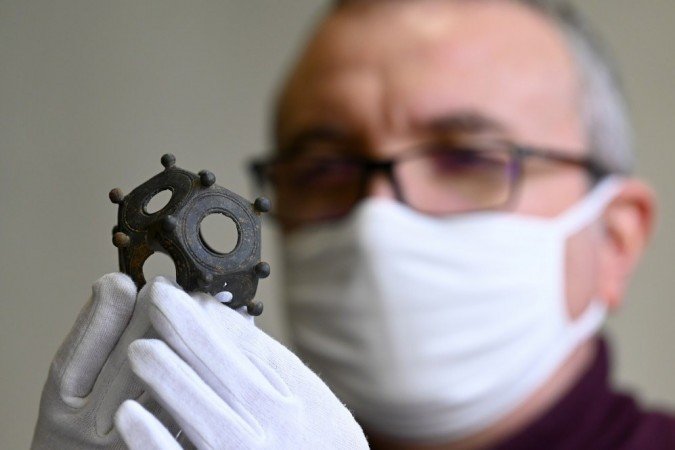 Um membro da DRAC (Diretoria Regional de Assuntos Culturais da Lorraine) inspeciona um dodecaedro romano ou dodecaedro galo-romano (uma pe&ccedil;a arqueol&oacute;gica muito rara datada dos s&eacute;culos II a IV DC).