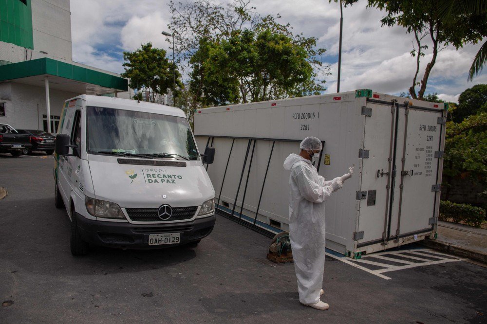 Trabalhadores da saúde usam roupas protetoras ao deixarem o corpo de uma vítima do novo coronavírus em um contêiner refrigerado do Hospital Público Vinte Oito de Agosto, unidade de tratamento de pacientes do COVID-19 em Manaus, Estado do Amazonas, Brasil, em 4 de janeiro de 2021