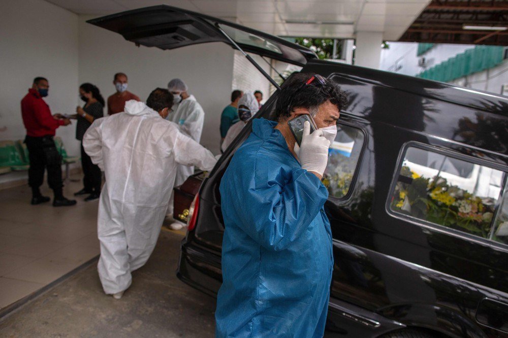 Trabalhadores da saúde usam roupas protetoras ao deixarem o corpo de uma vítima do novo coronavírus em um contêiner refrigerado do Hospital Público Vinte Oito de Agosto, unidade de tratamento de pacientes do COVID-19 em Manaus, Estado do Amazonas, Brasil, em 4 de janeiro de 2021