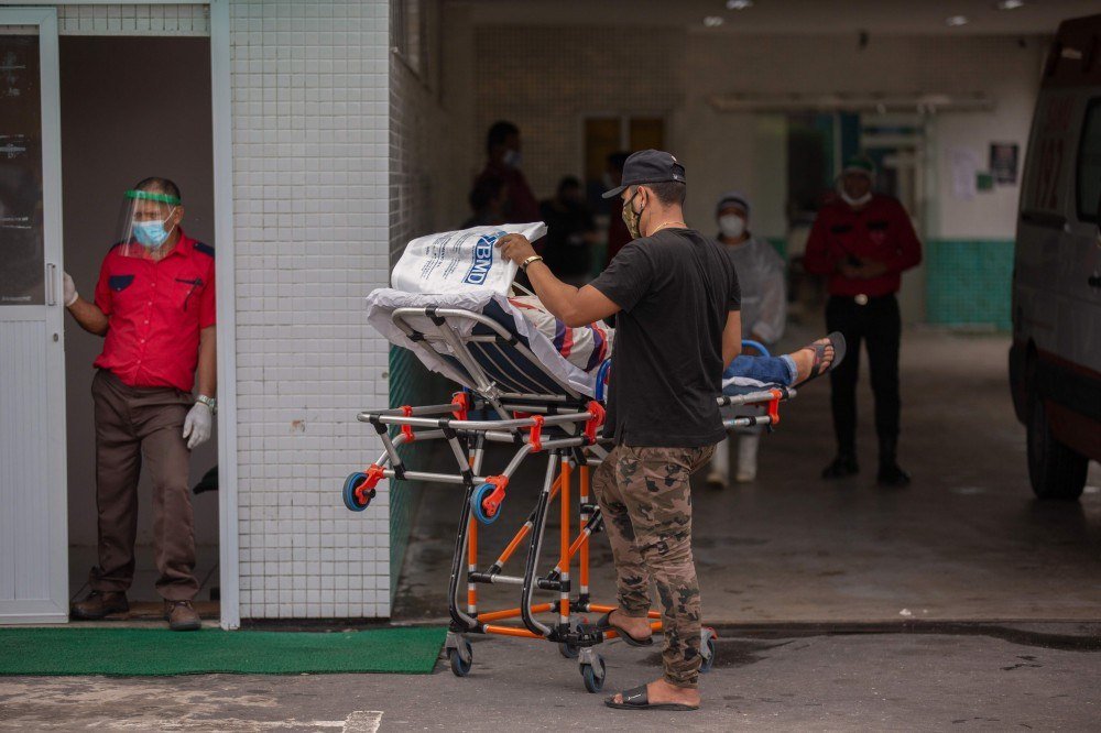 Trabalhadores da saúde usam roupas protetoras ao deixarem o corpo de uma vítima do novo coronavírus em um contêiner refrigerado do Hospital Público Vinte Oito de Agosto, unidade de tratamento de pacientes do COVID-19 em Manaus, Estado do Amazonas, Brasil, em 4 de janeiro de 2021