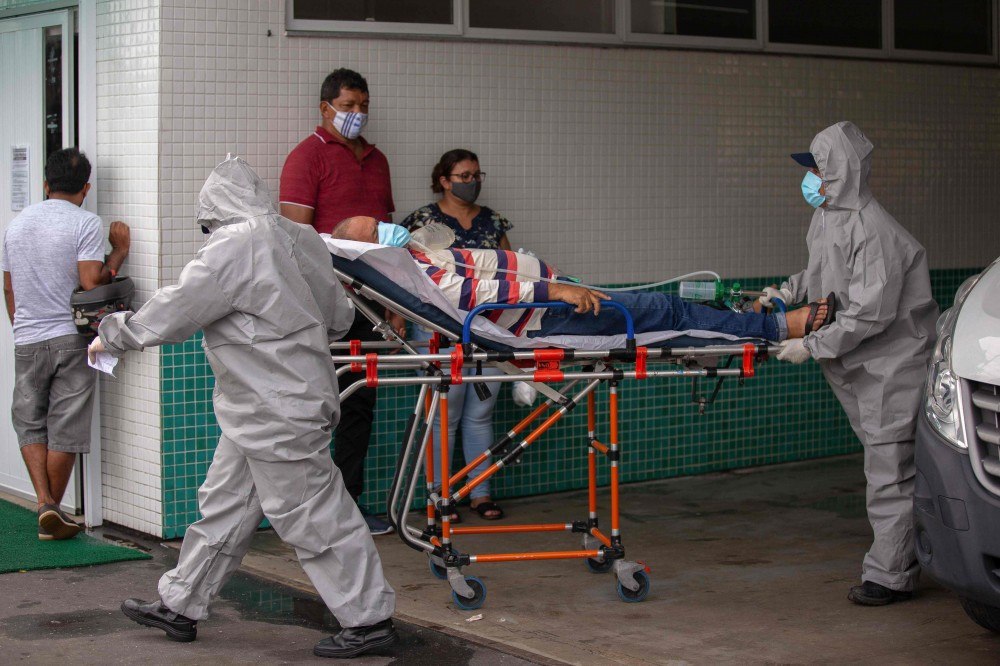 Trabalhadores da saúde usam roupas protetoras ao deixarem o corpo de uma vítima do novo coronavírus em um contêiner refrigerado do Hospital Público Vinte Oito de Agosto, unidade de tratamento de pacientes do COVID-19 em Manaus, Estado do Amazonas, Brasil, em 4 de janeiro de 2021