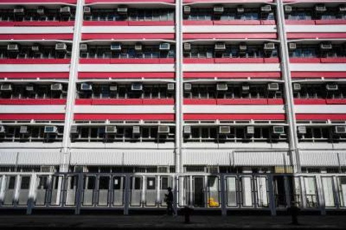 A pedestrian walks past a building with air-conditioning units on the exterior in Hong Kong on January 15, 2021. / AFP / Anthony WALLACE
