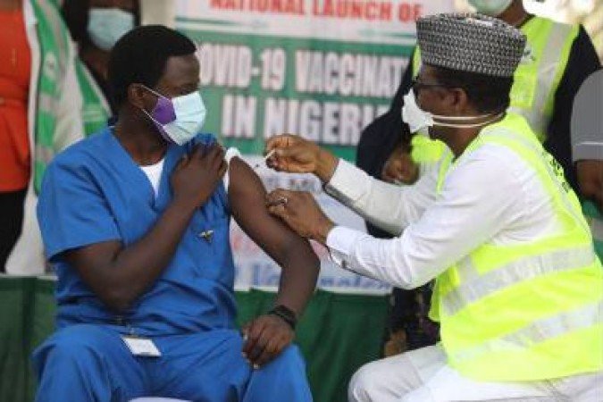Dr. Ngong Cyprian (L), the first Nigerian to receive the first dose of the Oxford/AstraZeneca vaccine at the National Hospital Abuja, Nigeria on March 5, 2021. The Nigerian Government begins its roll-out of nearly 4 million of the Oxford/AstraZeneca vaccine in Nigeria  / AFP / Kola Sulaimon