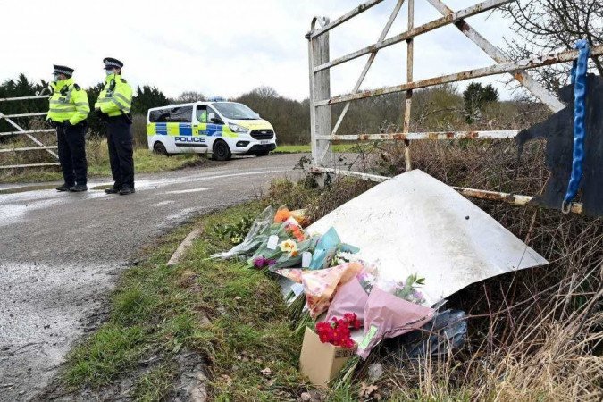 Flores e mensagens de condolências para Sarah Everard são vistas como policiais patrulhando perto da floresta onde policiais encontraram restos humanos perto de Ashford, sudeste da Inglaterra, em 12 de março de 2021. -  (crédito: Glyn KIRK / AFP)