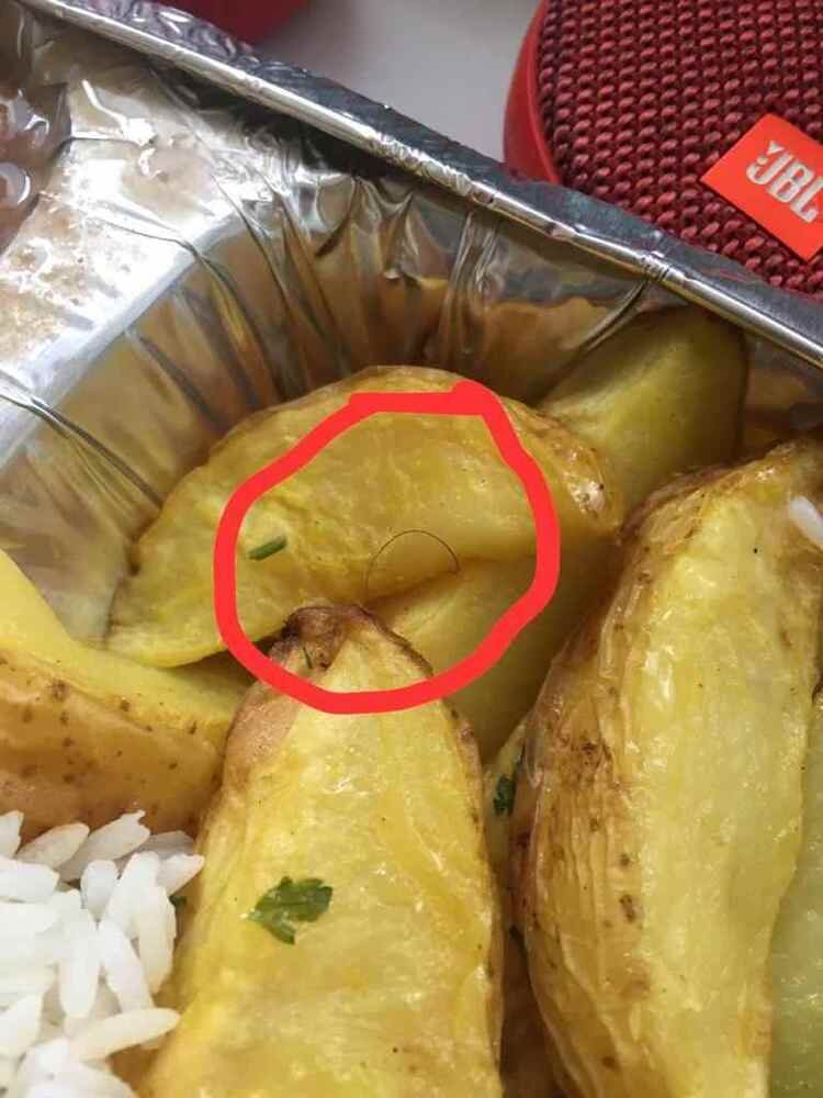 Marmita de alumínio com pedaços e batata assada. Há um fio de cabelo no meio das batatas