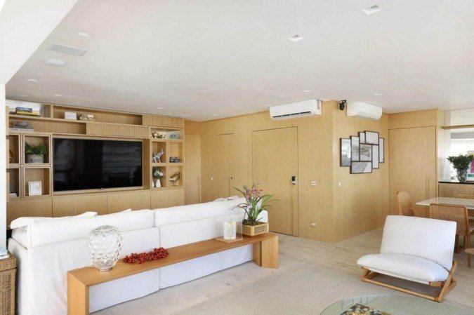 Todo o ambiente da arquiteta Helô Marque tem as paredes de madeira como fio condutor. As portas ficam completamente mimetizadas e os móveis da sala de jantar também se misturam ao espaço. No projeto, a mimetização harmonizou a sala