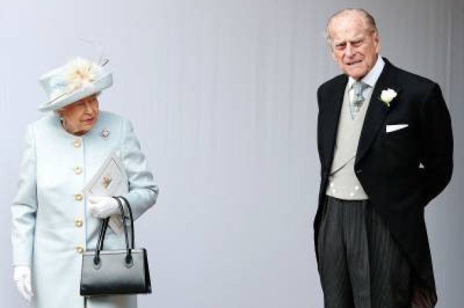(FILES) In this file photo taken on October 12, 2018 Britain's Queen Elizabeth II (L) and Britain's Prince Philip, Duke of Edinburgh (R) wait for the carriage carrying Princess Eugenie of York and her husband Jack Brooksbank to pass at the start of the procession after their wedding ceremony at St George's Chapel, Windsor Castle, in Windsor. Queen Elizabeth II's record-breaking reign has been marked by a commitment to duty despite personal setbacks, but the death of her husband will put that stoicism to the ultimate test.  The 94-year monarch now faces the twilight of her reign without her most trusted advisor and personal confidant, raising questions about how she will cope in running a family mired in crisis and scandal. / AFP / POOL / Alastair Grant