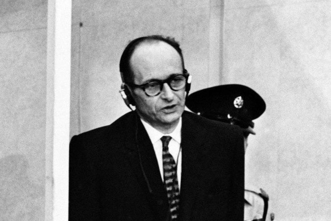 Esta foto de arquivo tirada em 11 de abril de 1961 mostra o criminoso de guerra nazista Adolf Eichmann em pé em seu cais à prova de balas durante o primeiro dia de seu julgamento em frente a um tribunal israelense, 11 de abril de 1961, em Jerusalém -  (crédito: Arquivos/AFP)
