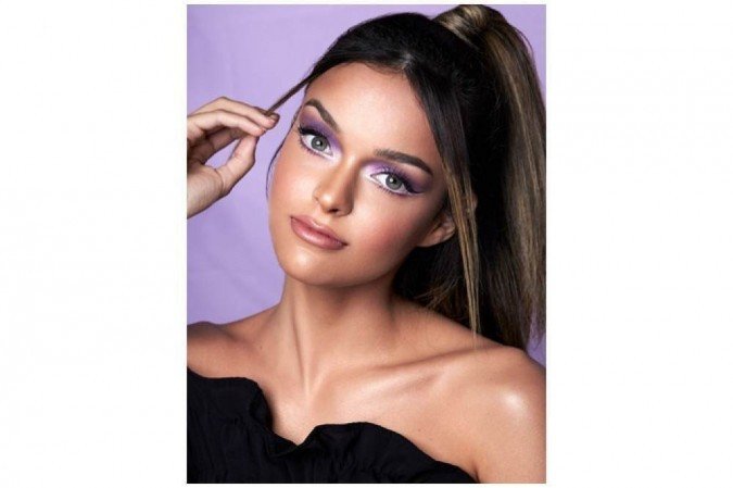 Isabel De Santis fez uma make com tom lilás alongado, delineado colorido e cantinhos iluminados com sombra branca na modelo Larissa Amorim
