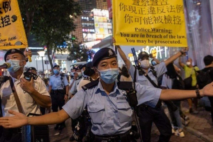 Policiais seguram cartazes com aviso de risco de pris&atilde;o e processo judicial caso haja manifesta&ccedil;&atilde;o