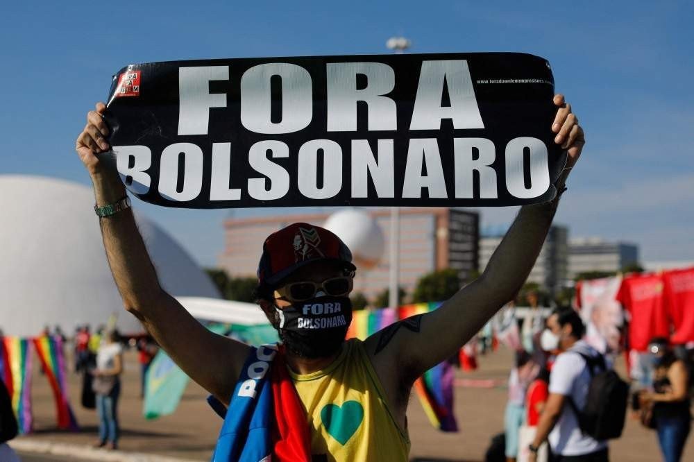Um ativista segura uma placa durante um protesto de partidos de oposição e movimentos sociais contra o manejo da pandemia COVID-19 em Brasília pelo presidente brasileiro Jair Bolsonaro, em 19 de junho de 2021. - O presidente de extrema direita Jair Bolsonaro vem enfrentando críticas por sua O controle da pandemia, incluindo a recusa inicial de ofertas de vacinas, como alertam os epidemiologistas, o Brasil pode agora estar à beira de uma terceira onda de Covid-19. (Foto Sergio Lima / AFP)