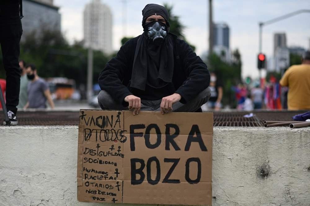 Um manifestante segura uma placa durante um protesto contra o tratamento da pandemia Covid-19 pelo presidente brasileiro Jair Bolsonaro no Rio de Janeiro, Brasil, em 19 de junho de 2021. O presidente de extrema direita Jair Bolsonaro tem enfrentado críticas por sua gestão da pandemia, incluindo recusando inicialmente as ofertas de vacinas, como alertam os epidemiologistas. O Brasil pode agora estar à beira de uma terceira onda de Covid-19.