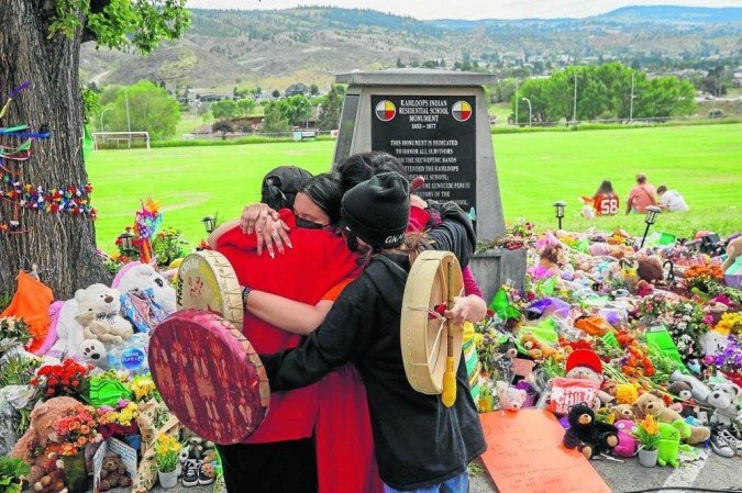 Membros da etnia Mosakahiken Cree se abraçam diante de memorial improvisado para honrar 215 crianças enterradas em Kamloops: novas covas - (crédito: Cole Burston/AFP) Membros da etnia Mosakahiken Cree se abraçam diante de memorial improvisado para honrar 215 crianças enterradas em Kamloops: novas covas - (crédito: Cole Burston/AFP)