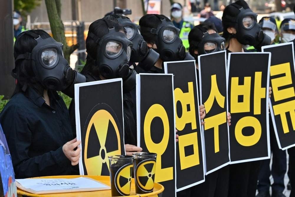 Ativistas ambientais sul-coreanos usando máscaras de gás seguram cartazes durante um protesto contra a decisão do Japão de despejar águas residuais de Fukushima no mar, perto da embaixada japonesa em Seul