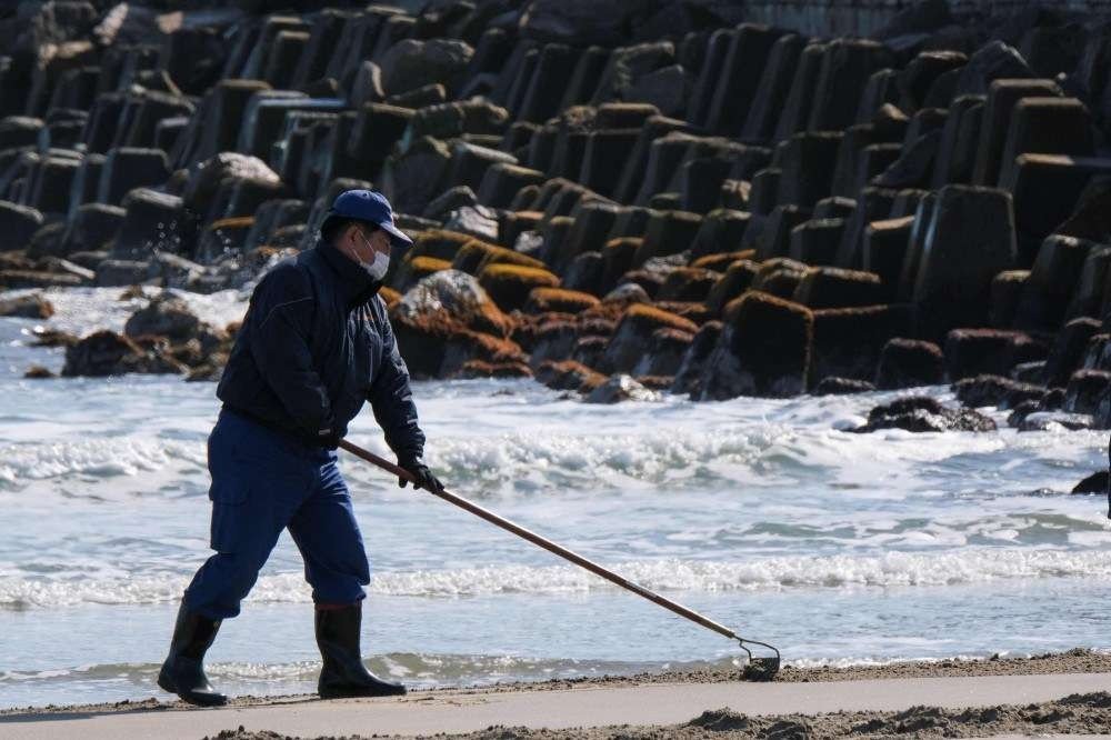 Membros da brigada de incêndio da cidade de Tomioka conduzem operações para procurar pistas sobre pessoas desaparecidas desde os desastres de 2011, nas margens perto da Usina Nuclear de Fukushima Daini em Tomioka