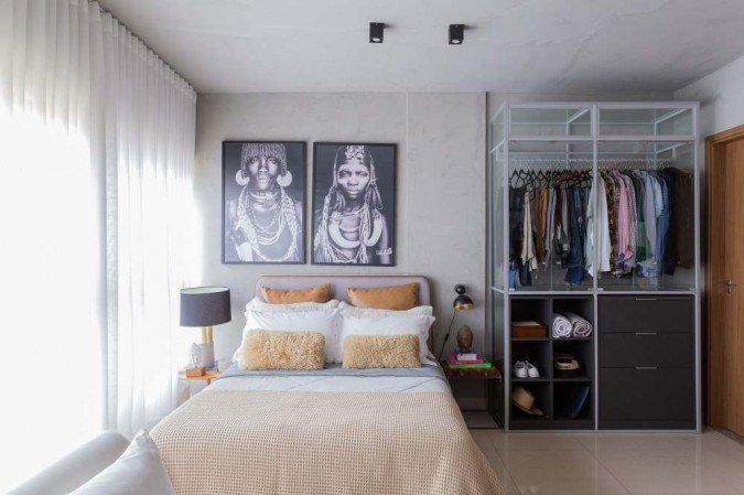 Esse espaço é o quarto do morador. As paredes claras, perto das cortinas brancas, dão um ar de continuidade e o ambiente fica mais fluido. As cores neutras do armário e dos objetos de decoração contribuem para essa sensação