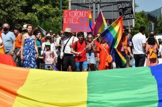People walk behind a rainbow flag during the second Sarajevo Pride parade on August 14, 2021. Several hundreds of LGBTQI participants demanded for equal rights in all aspects of life during the march, which took place under the police protection to avoid incidents. (Photo by ELVIS BARUKCIC / AFP) - (crédito: ELVIS BARUKCIC) People walk behind a rainbow flag during the second Sarajevo Pride parade on August 14, 2021. Several hundreds of LGBTQI participants demanded for equal rights in all aspects of life during the march, which took place under the police protection to avoid incidents. (Photo by ELVIS BARUKCIC / AFP) - (crédito: ELVIS BARUKCIC)