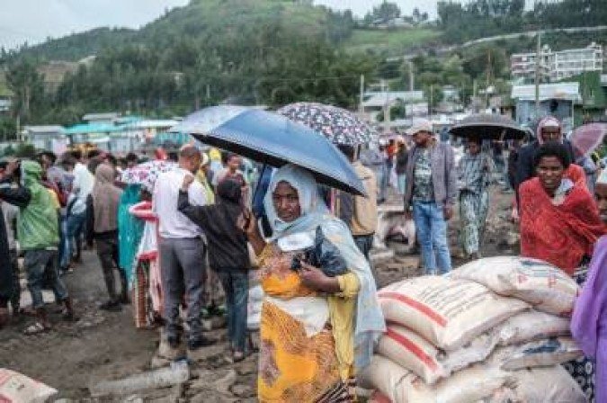 A woman stands with an umbrella next to sacks of rice during a food distribution for internally displaced people (IDP) from Amhara region, in the city of Dessie, Ethiopia, on August 23, 2021. Long confined to Tigray, the conflict in Ethiopia has recently spread to two neighbouring regions, Afar and Amhara, with heavy weapons fire killing an untold number of civilians and displacing hundreds of thousands more.  (Photo by EDUARDO SOTERAS / AFP)