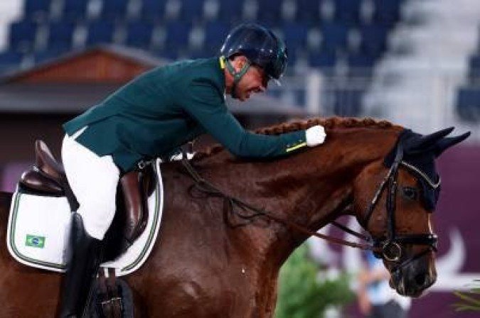 Brazil's Rodolpho Riskalla riding Don Henrico hugs his horse after competing in the equestrian dressage individual test grade IV during the Tokyo 2020 Paralympic Games at Equestrian Park in Tokyo on August 26, 2021. (Photo by Behrouz MEHRI / AFP)