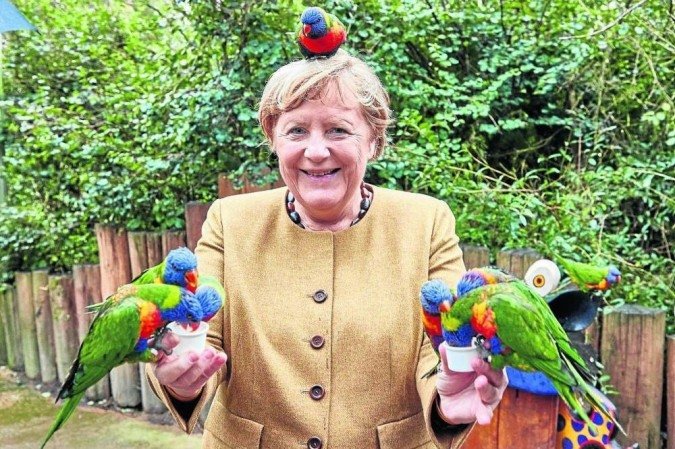 Merkel sorri ao alimentar periquitos no Parque dos Pássaros de Marlow, no norte do país: carisma e liderança da mulher mais poderosa do mundo -  (crédito: GEORG WENDT)