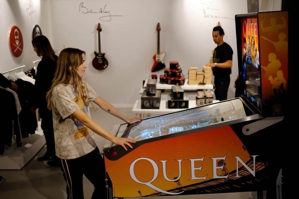 A shop assistant plays on a pinball machine at the newly opened store of legendary British rock group Queen in central London on September 27, 2021.
