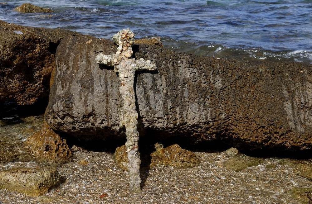 A picture taken on October 19, 2021, shows an ancient one-meter-long sword that experts say dates back to the Crusader-era and is believed to have belonged to a Crusader, displayed at the beach in the Israeli seaport of Caesarea, some days after being discovered by a local diver. (Photo by Jack GUEZ / AFP)