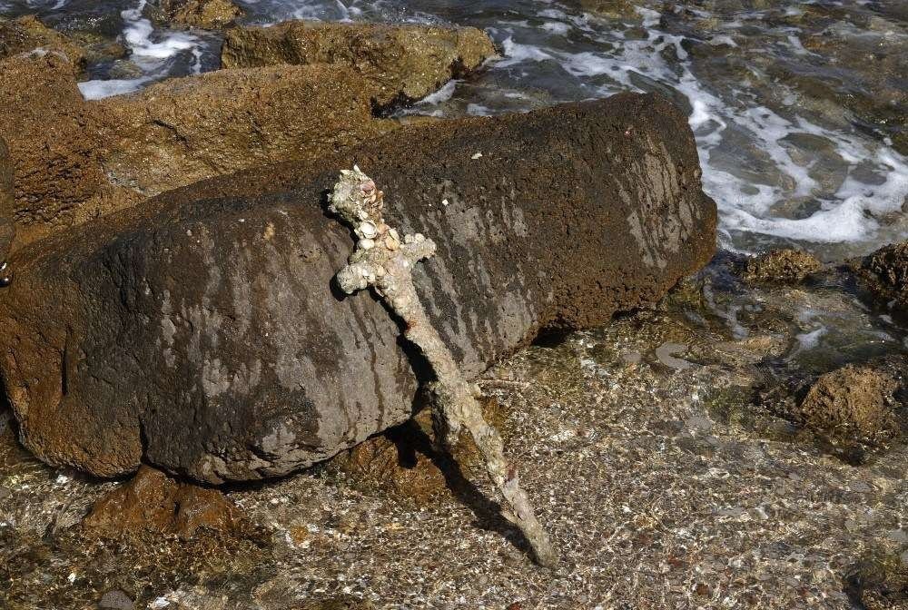A picture taken on October 19, 2021, shows an ancient one-meter-long sword that experts say dates back to the Crusader-era and is believed to have belonged to a Crusader, displayed at the beach in the Israeli seaport of Caesarea, some days after being discovered by a local diver. (Photo by Jack GUEZ / AFP)
