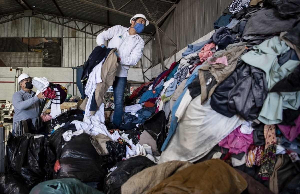  Men work at a factory that recycles used clothes discarded in the Atacama desert for wooden isolation panels for the walls of social housing, in Alto Hospicio, Iquique, Chile, on September 27, 2021. - EcoFibra, Ecocitex and Sembra are circular economy projects that have textile waste as their raw material. The textile industry in Chile will be included in the law of Extended Responsibility of the Producer (REP), forcing clothes and textiles importers take charge of the waste they generate. (Photo by MARTIN BERNETTI / AFP)
      Caption 